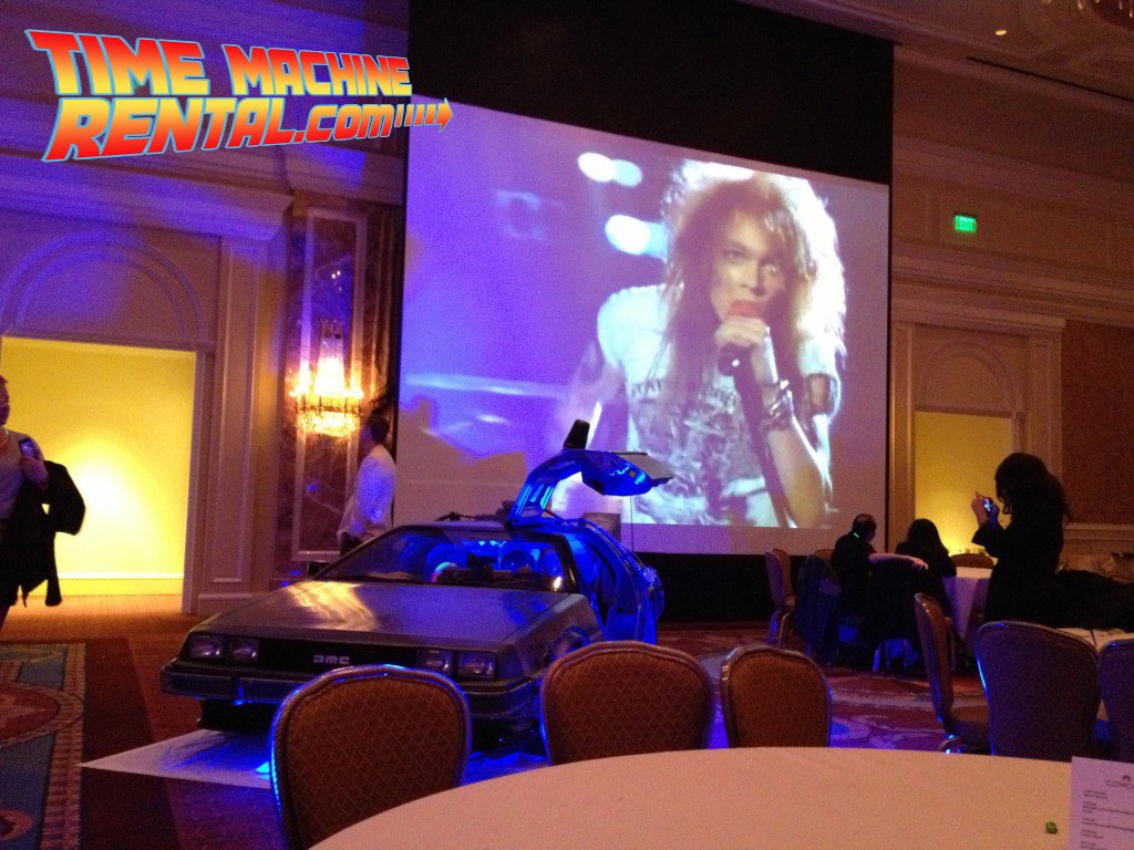 Classic 80's videos blast on the screen as the DeLorean Time Machine rental car stands ready to accept party guests.